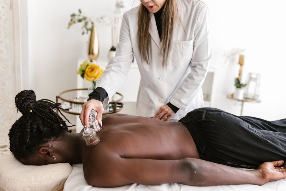 A therapist performs cupping therapy on a man at a spa for relaxation and pain relief.