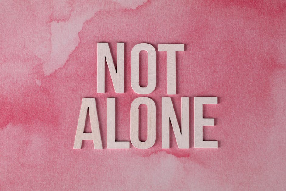 The phrase 'Not Alone' on a pink watercolor background conveys support and hope.