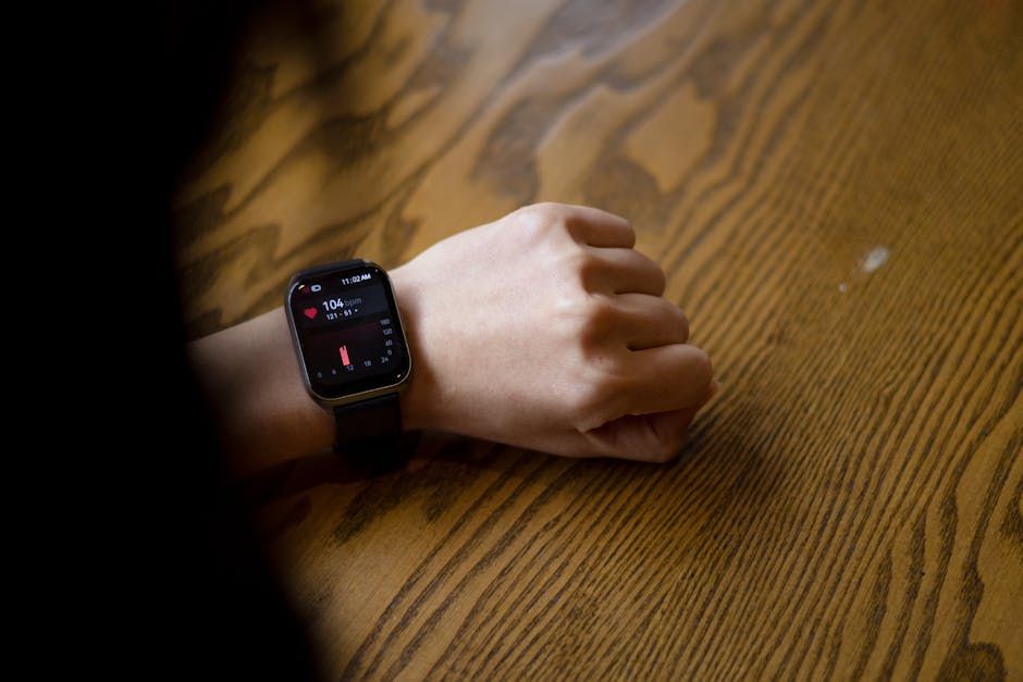 A person checks heart rate on smartwatch showing 104 bpm on wooden table.
