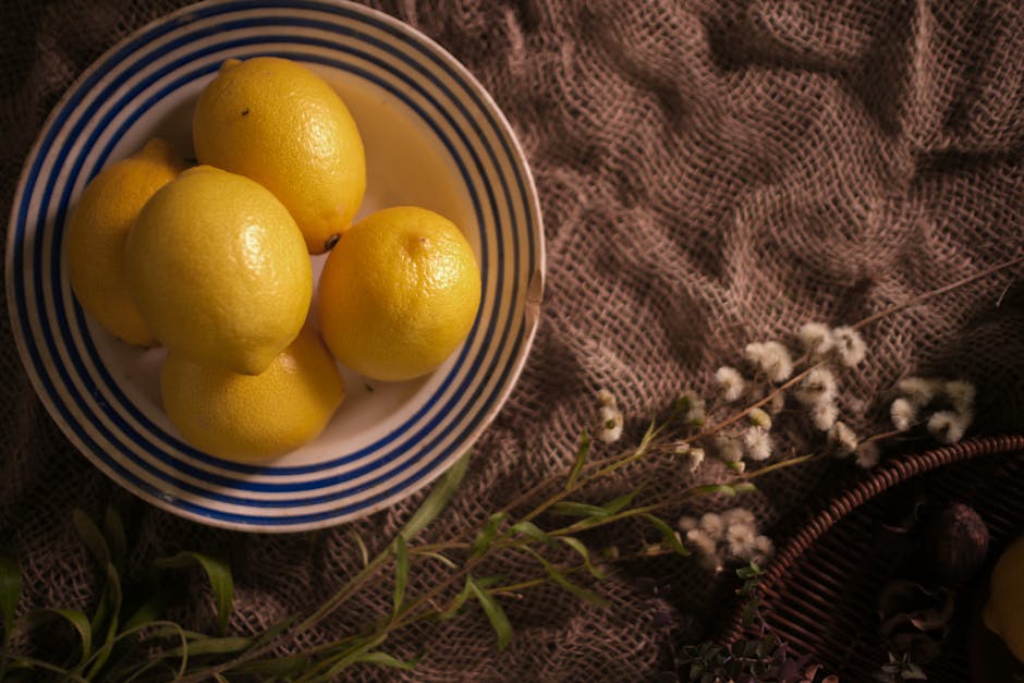 Aesthetic arrangement of lemons in a striped bowl with rustic textured backdrop.