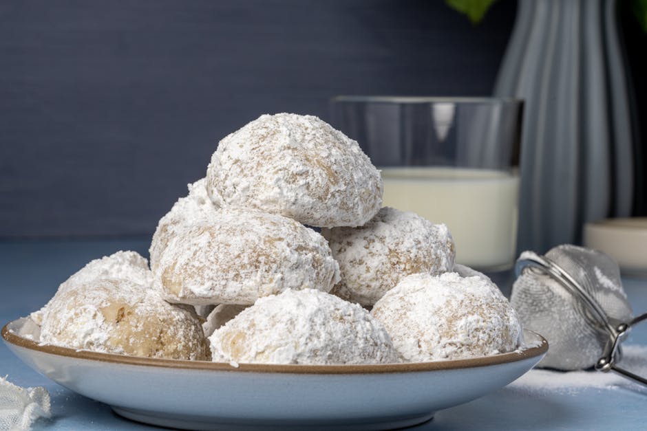 Delicious kourabiedes cookies dusted with powdered sugar on a ceramic plate, perfect for celebrations.