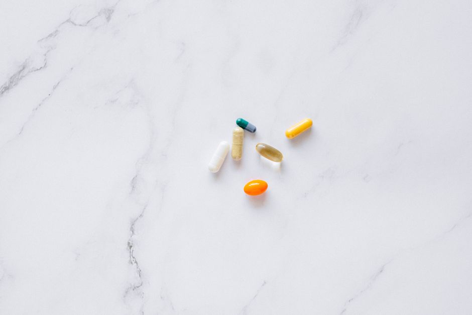 A variety of colorful pills arranged on a white marble surface, representing healthcare.