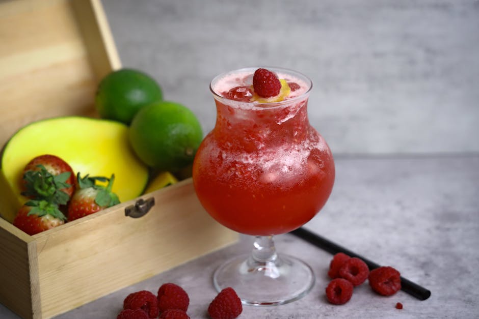 Chilled raspberry lemonade served with fresh fruits including mango, lime, and strawberries for a healthy refreshment.