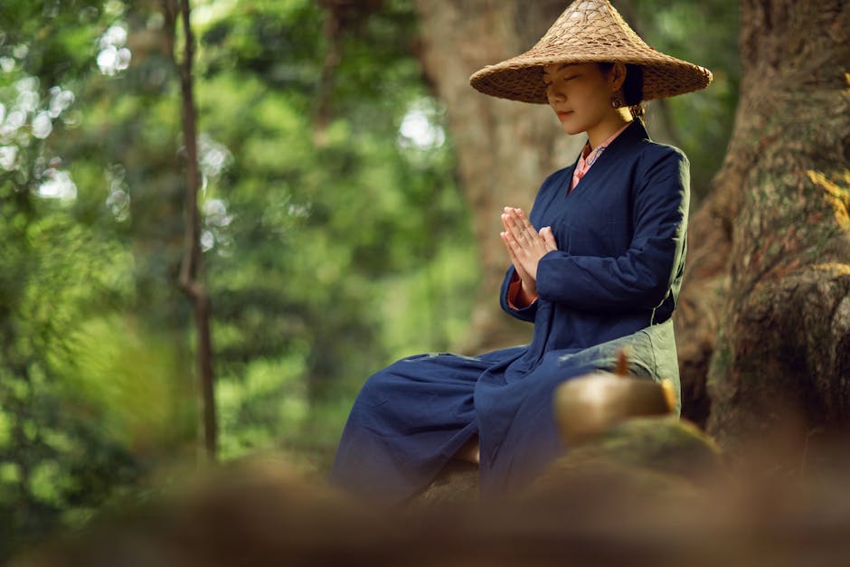 Woman in traditional Asian attire meditating outdoors, embracing tranquility and nature.